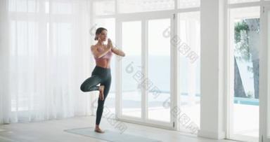 Keep your balance in check. 4k video footage of a young woman doing yoga at home